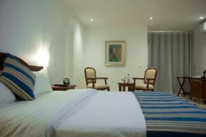 ein Schlafzimmer mit einem großen Bett mit zwei Stühlen in der Unterkunft Hôtel Millennium Kamissa in Bamako