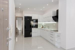 a kitchen with white cabinets and a black refrigerator at Despina's Luxury apt downtown in Heraklio