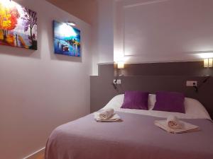 グラナダにあるApartamentos Navas 16のベッドルーム1室(紫色の枕とタオル付きのベッド1台付)