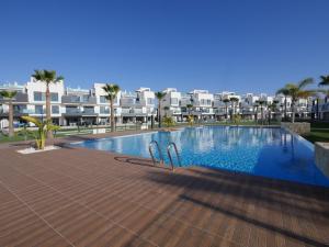 uma piscina com duas cadeiras em frente a alguns edifícios em oasis beach casa Georgio em Guardamar del Segura