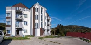 duży biały budynek z wzgórzem w tle w obiekcie Apartament Widokowy - 5D Apartamenty w Świeradowie Zdroju