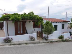a small white house with a white fence and flowers at Theathina in Kalamaki Heraklion +3 photos