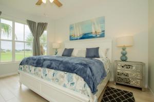 a bedroom with a bed with a blue comforter at GreenLinks Golf View Villa Mustang at Lely Resort in Naples +70 photos