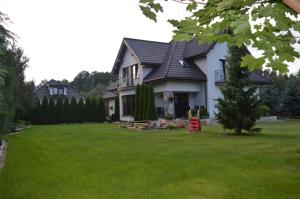 a white house with a green yard with a house at Zacisze in Rozalin