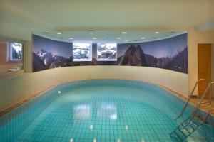 a swimming pool with two monitors on the wall at Hotel Menning ***S in Oberstdorf