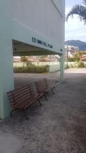 a wooden bench sitting in front of a building at Apartamento Peruíbe in Peruíbe