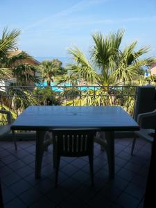 a blue table and chairs on a balcony with palm trees at Appartamento Rais Gerbi in Finale