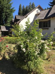 une maison avec une brousse fleurie devant elle dans l'établissement Posada del Angel, à San Carlos de Bariloche