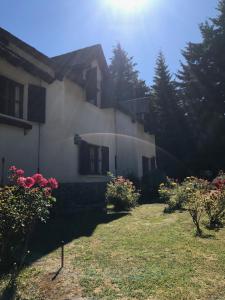 une maison avec des fleurs roses dans la cour dans l'établissement Posada del Angel, à San Carlos de Bariloche