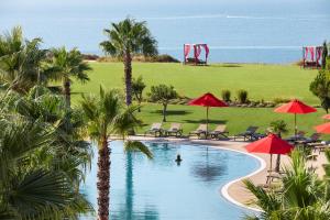 a swimming pool with palm trees and chairs and umbrellas at Cascade Wellness Resort in Lagos