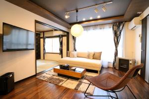 a living room with a couch and a tv at One’s Villa Sapporo House in Sapporo
