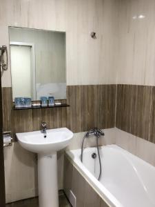 uma casa de banho com um lavatório, uma banheira e um espelho. em 土城飯店 em Tucheng