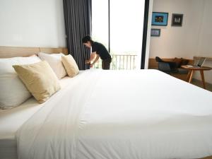 een man die naast een groot wit bed staat bij B Boutique Residence in Suratthani