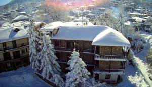 ein schneebedecktes Gebäude mit einem Weihnachtsbaum in der Unterkunft Guesthouse Alexandra in Eptalofos