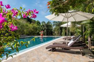 a swimming pool with two chairs and an umbrella at Kep Bungalows in Kep