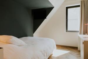 a bedroom with a white bed and a staircase at Hotel Jerom in Kalmthout