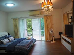 a bedroom with a bed and a television and a window at BAANTAI HOMESTAY in Chumphon