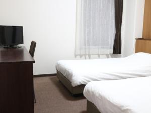 a hotel room with two beds and a flat screen tv at Hotel Sun Plaza Sakai in Sakai