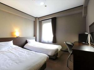 a hotel room with two beds and a desk and a window at Hotel Sun Plaza Sakai in Sakai