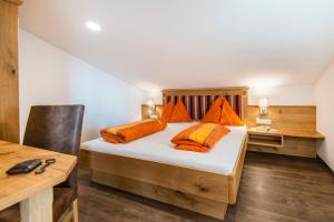 a bedroom with a bed with orange pillows and a desk at Ferienbauernhof Elmaugut in Mühlbach am Hochkönig