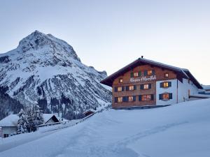 レッヒにあるPension Alpenfluhの雪山を背景にした建物