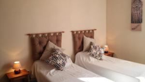 two beds in a room with two lamps on tables at Domaine du Barvy in Odenas