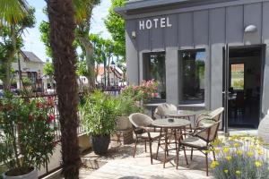 un patio avec des chaises et des tables en face d'un hôtel dans l'établissement Boutique Hôtel d'Orbigny Chatelaillon - La Rochelle, à Châtelaillon-Plage