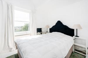 a white bedroom with a large bed and a window at Bright and stylish 1 bedroom apt in Notting Hill in London