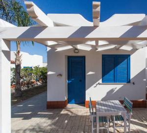 una casa blanca con una puerta azul y una mesa en Petruso Resort, en Balestrate