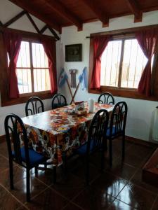 comedor con mesa, sillas y ventanas en Mi Refugio en Río Gallegos
