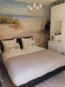1 dormitorio con 1 cama y una pintura de playa en Bed & Breakfast Zeeduinsepoort, en Oostkapelle