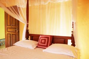 a bedroom with a canopy bed with two pillows at Ariyadasa Guest House in Galle