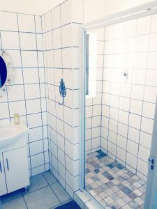 a bathroom with a shower with white tiled walls at Kairos Cottage B&B in Lüderitz