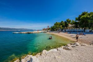 a beach with people sitting on the sand and the water at Hotel Sveti Kriz in Trogir