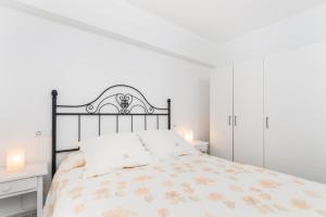 ein weißes Schlafzimmer mit einem Bett und zwei Lampen in der Unterkunft APARTAMENTO LOS GIRASOLES in Alcúdia
