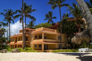 a large yellow building on the beach with palm trees at Villas Chiara Punta Cana in Punta Cana
