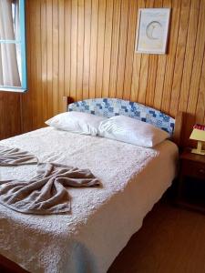 a bedroom with a bed with a wooden wall at Pousada Fazenda A CASA DO MORRO in Cambará