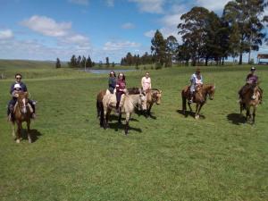 a group of people riding horses in a field at Pousada Fazenda A CASA DO MORRO in Cambara do Sul