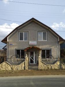 un edificio gris con porche y puerta en Лелека, en Dilyatyn
