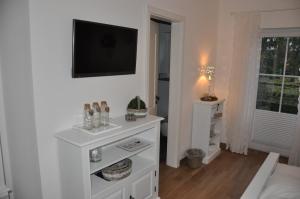 sala de estar con TV en la pared en White Cottage Garden en Cloppenburg