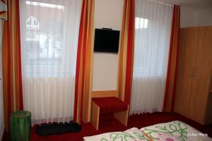 1 dormitorio con cortinas de color naranja, 1 cama y TV en Donau Pension en Tuttlingen