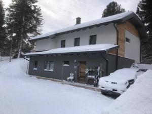 a snow covered house with a car parked in front of it at Grünseeappartement in Turracher Hohe