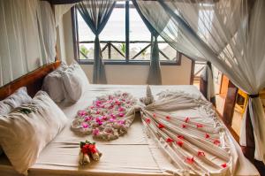 a white bed with pink flowers on it at Kendwa Beach BnB in Kendwa