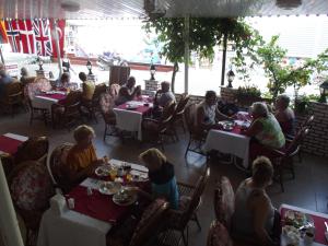 a group of people sitting at tables in a restaurant at Derya Motel in Side