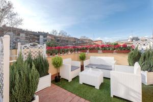 a rooftop patio with white furniture and flowers at Hotel Infinito - Gruppo BLAM HOTELS in Rome