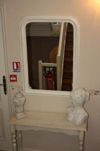 a mirror over a table with a white statue on it at La Marjolaine in Juan-les-Pins