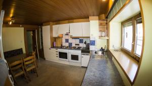 a kitchen with white cabinets and a sink and a table at Gästehaus Auer in Sankt Leonhard im Pitztal