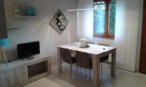 stół jadalny z krzesłami i telewizor w obiekcie Shabby house Donatella w mieście Carenno