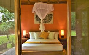 a bedroom with a bed with an orange wall at Kuwera Eco Lodge in Sigiriya