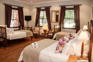 a hotel room with two beds and chairs and windows at Beaufort Manor Country Lodge in Beaufort West +235 photos
